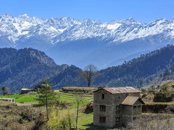 Une maison de pierre au-dessus de Gatlang, devant la chaîne enneigée